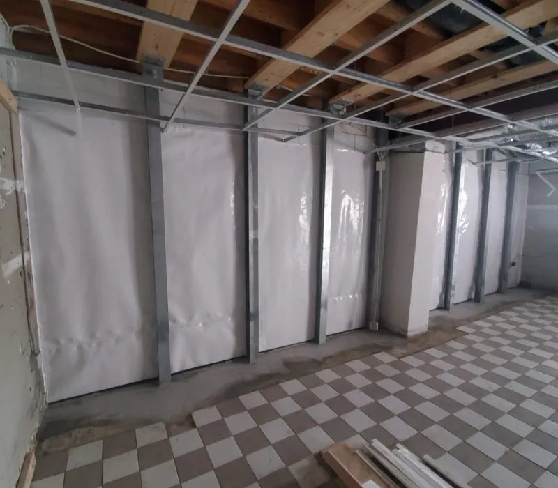 White vapor barrier membrane installed along walls for basement waterproofing